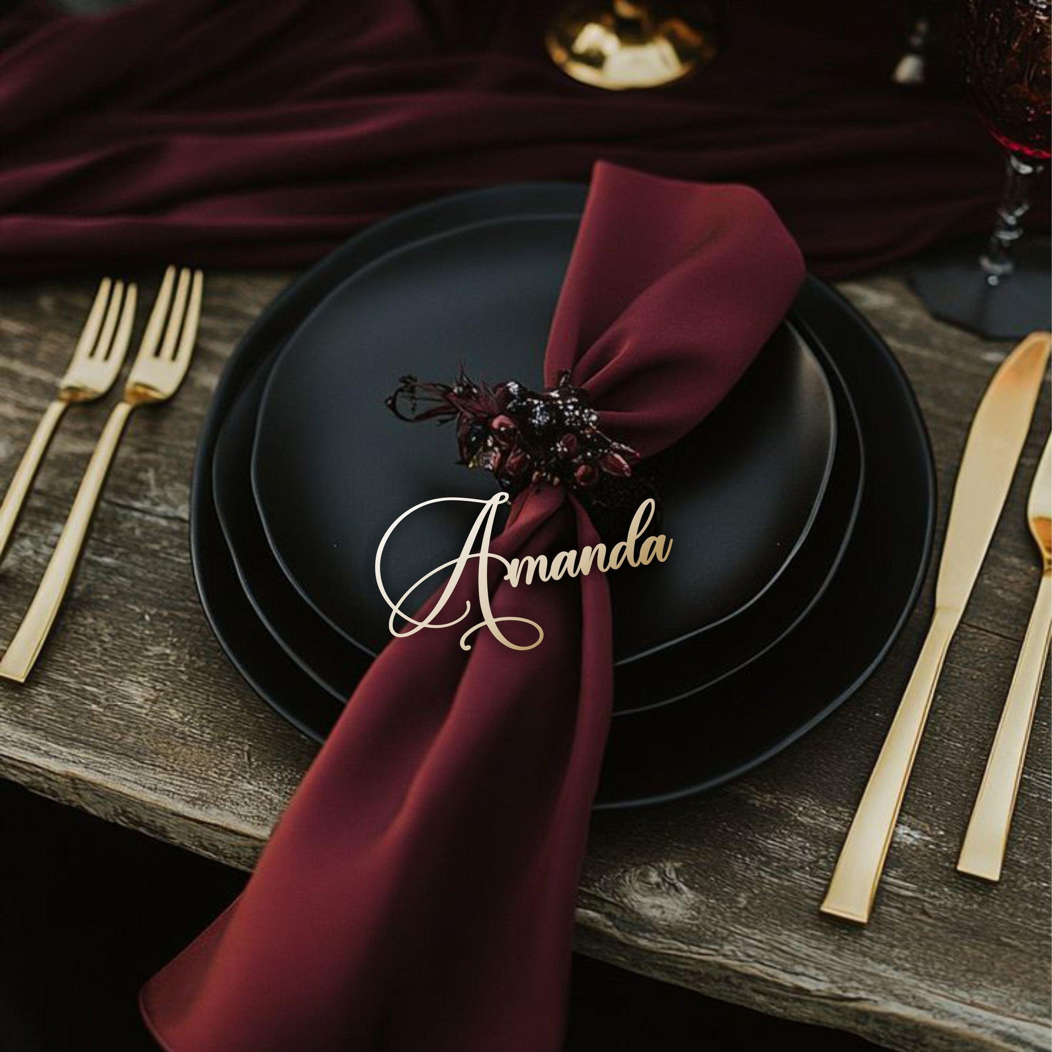Gold name tag “Amanda” on black plate with deep red ribbon and candle